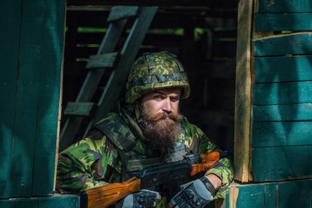 Bearded soldier with gun in the camouflage is ready for the fight