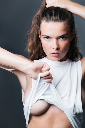 fashionable girl with pretty face slim model with stylish long brunette hair in white shirt in studio on grey backgroundの写真素材