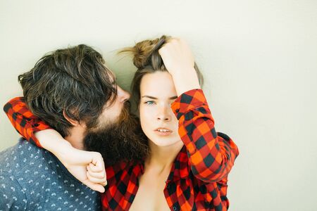 Young couple of pretty woman in checkered shirt and handsome bearded man with long beard outdoor on light backgroundの写真素材