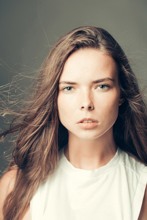 fashionable girl with pretty face slim model with stylish long brunette hair in white shirt in studio on grey backgroundの写真素材