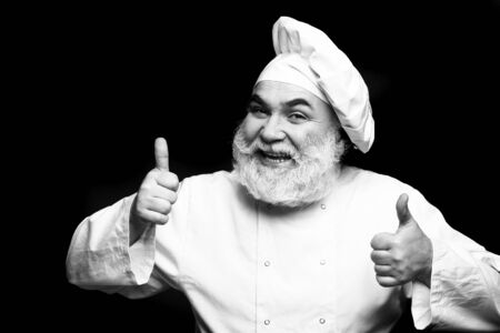 Bearded man cook with smiling face in chef hat with thumb up in studio, black and whiteの写真素材