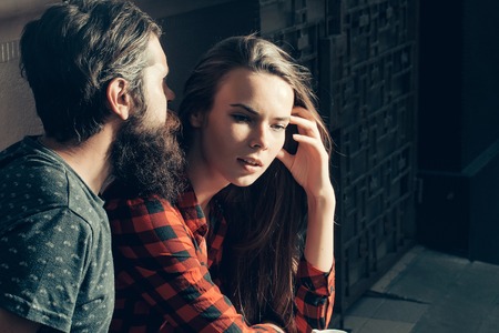 Pretty girl with long brunette hair listens to handsome man bearded hipster outdoors in street cafeの写真素材