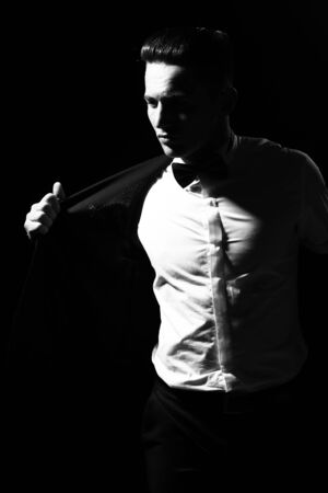 young handsome gentleman undressing fashion black suit in white shirt and bow tie in studio, black and whiteの写真素材