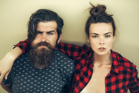 Young couple of pretty woman in checkered shirt and handsome bearded man with long beard outdoor on light backgroundの写真素材