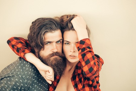 Young sexy couple of pretty woman in checkered shirt and handsome bearded man with long beard outdoor on light backgroundの写真素材