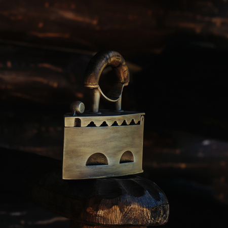 old fashioned retro metallized heavy antique iron tool for ironing with decorative steel and wooden handle with animal head on wood backgroundの写真素材