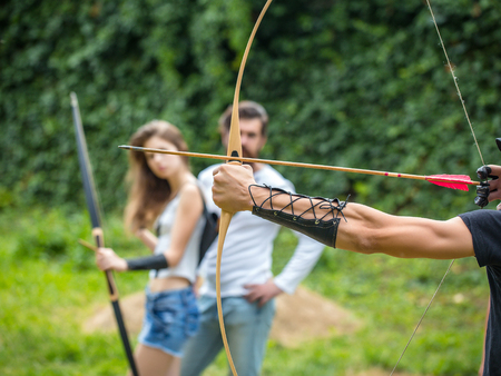 Handsome man is ready to shoot and the couple watches. Attractive couple learns how to use the bowの写真素材