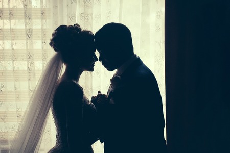 Silhouette of bride beautiful young woman and groom handsome african American man share love head to...