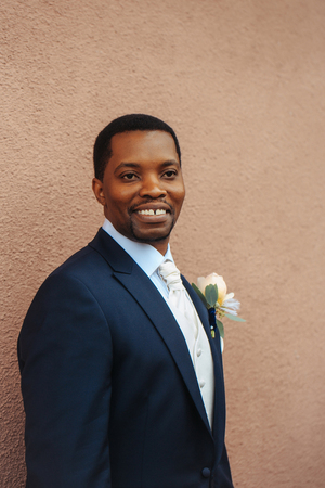 Smiling man african American groom in elegant suit coat with white tie and flower boutonniere for wedding ceremonyの写真素材