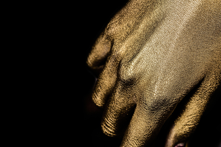 female golden or gold hand or arm with palm and fingers with body art painted metallized color on black background, closeup, , copy spaceの写真素材