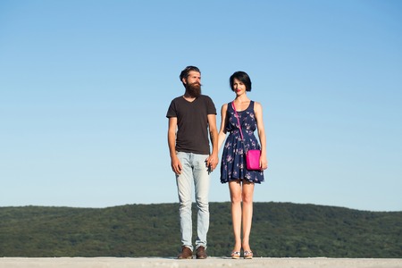 Young couple of man bearded hipster and beautiful brunette woman pose on blue sky on mountain sceneの写真素材