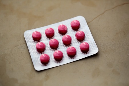 Red tablets pills in blister pack medication package on beige backgroundの写真素材