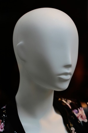 Fashion female mannequin bald in leisure wear clothes in shop on dark background