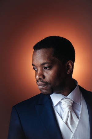 Handsome man african American groom in elegant suit coat with white tie and shirt for wedding ceremonyの写真素材