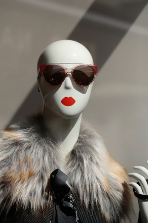 Fashion female mannequin bald in glamorous sunglasses and fur coat in shop on grey backgroundの写真素材