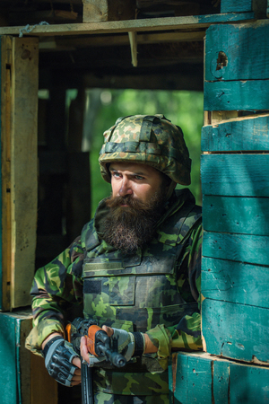 Portrait of bearded soldier in camouflage and gunの写真素材