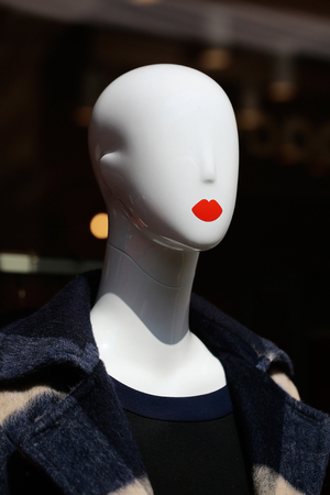 Fashion female mannequin bald in warm coat clothes in shop on grey backgroundの写真素材