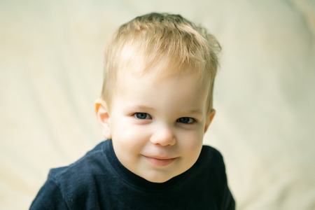 Small boy child with smiling cute face and blue eye blond closeup on light backgroundの写真素材