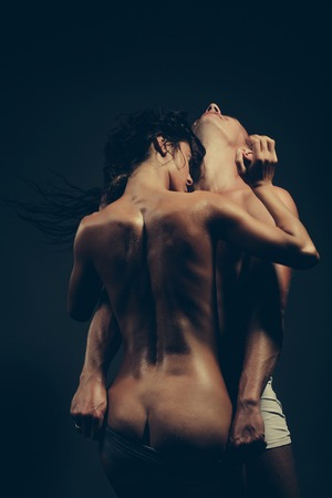 young couple of pretty slim sporty woman with long curly hair and sexy buttocks and handsome muscular man with fit body topless in panties on studio backgroundの写真素材