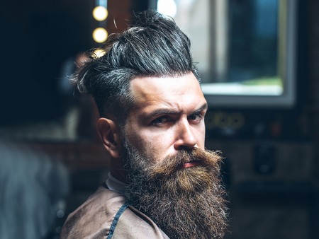 Handsome brunette hipster with stylish haircut and thick beard with serious face expressionの写真素材