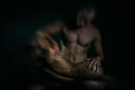 blurred or defocused young sexy couple of pretty slim naked woman with slim body and cute buttocks touched by handsome muscular man in studioの写真素材