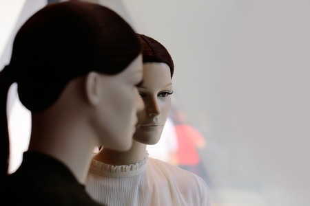 Two fashion female mannequins in brown wigs with long tail display casual clothes in shop on grey backgroundの写真素材