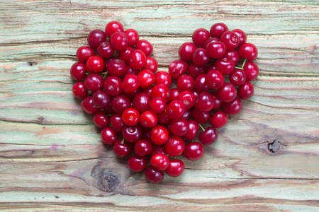 fresh seasonal cherry berry fruit red color with healthy vitamins on wooden or wood table laying in shape of heart as love symbol of valentines day holidayの写真素材