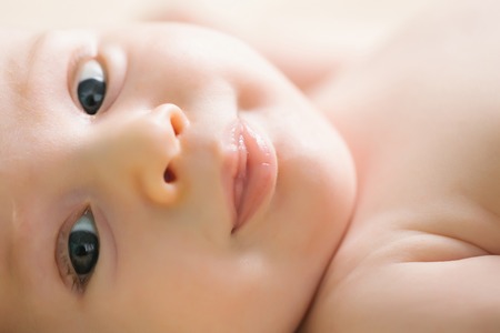 Little boy baby newborn with cute adorable face closeup on light backgroundの写真素材
