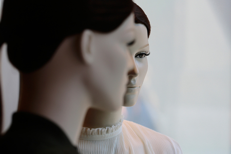 Two fashion female mannequins in brown wigs with long tail display casual clothes in shop on grey backgroundの写真素材