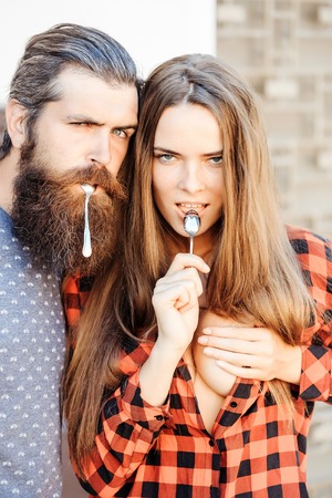 young couple of pretty girl with long hair and handsome bearded man hipster with beard holding metallized tea spoon outdoorの写真素材