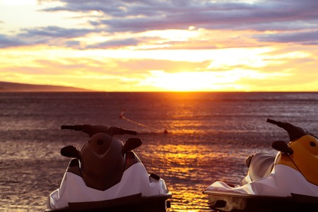 red scooters over dark twilight sky on beach with sea or ocean water on evening sunset natural backgroundの写真素材