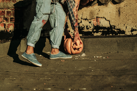 Halloween pumpkin traditional autumn holiday symbol with bearded bloody man zombie hipster on asphalt roadの写真素材