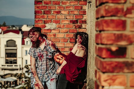 Halloween zombie couple of bearded man hipster or war soldier and bloody young woman with wounds and...