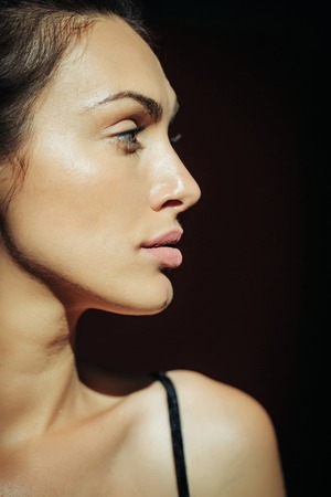 Young girl with pretty sexy serious face glamour makeup red lips perfect healthy skin attractive eyes side view profile on black background studio closeupの写真素材