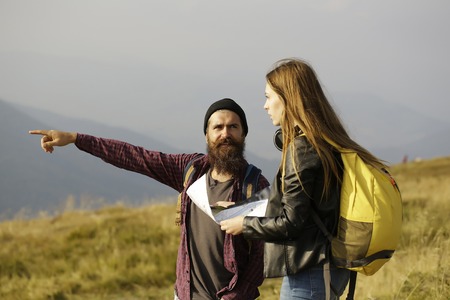 Bearded man hipster with beard and moustache and pretty girl young beautiful woman explore route with map on mountain top on foggy skyの写真素材