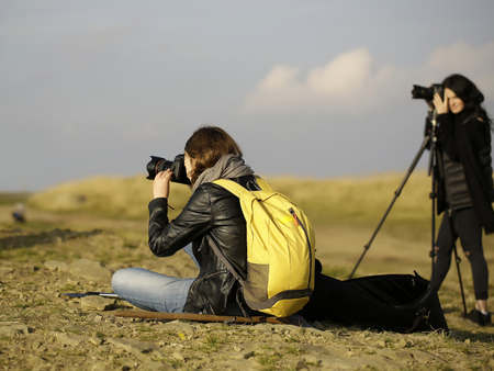 Two pretty girls young women travelers take photograph on mountain top on foggy sky