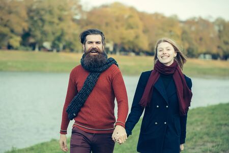 Young couple of pretty girl and bearded man hipster walk outdoors in park on autumn day on natural backgroundの写真素材