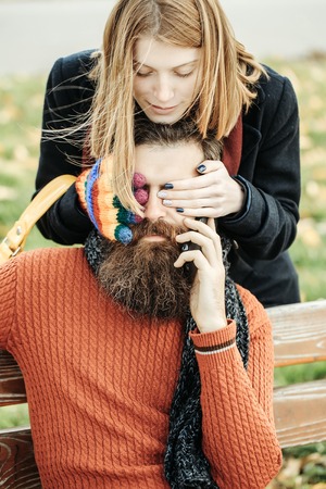 Pretty girl young beautiful woman with red hair plays peekaboo with bearded man hipster with beard...