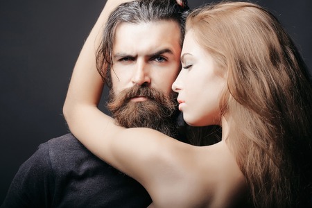 bearded handsome man and female slim flexible body of young pretty sexy woman or girl has long blonde hair embracingの写真素材