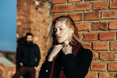 Young couple of pretty cute girl or beautiful sexy woman and handsome bearded man hipster with beard sunny outdoor on roof near red brick wall backgroundの写真素材