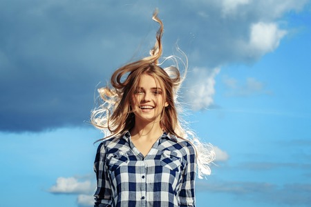 Pretty girl young beautiful woman with long curly blond hair in shirt jumps smiling outdoors on...