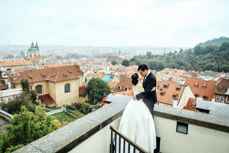 Chinese bride and groom young cute newlyweds just married couple hug outdoors on roof on cityscape backgroundの写真素材