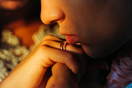 Young groom man holding bridal female hand with golden ring near his mouth closeup in sunny wedding dayの写真素材