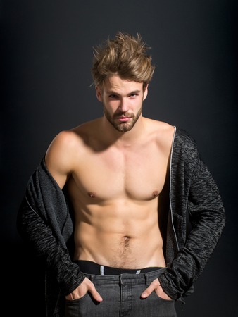 young handsome bearded sexy macho man with long beard and stylish hair in jacket and pants with muscular bare torso in studio on black backgroundの写真素材