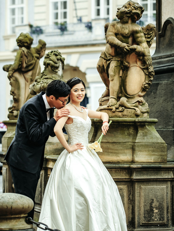 Chinese cute happy smiling bride and groom young newlyweds just married couple in streets of old city on wedding day near stony fountainの写真素材