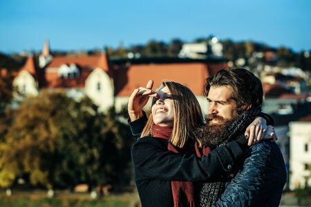 Young happy couple of pretty girl and bearded man hipster embracing outdoors in park on autumn day on natural background near housesの写真素材