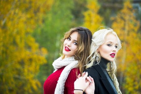 young pretty sexy women or girls with cute face and long blond hair has red lipstick on lips in scarf outdoor on autumn natural background, copy spaceの写真素材
