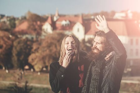 Young couple of pretty girl and bearded man hipster laugh outdoors on sunny autumn day on cityscape...