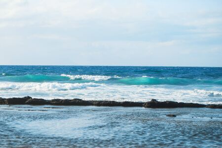 sea or ocean foaming waves rolled on coast with blue sky horizon as natural background