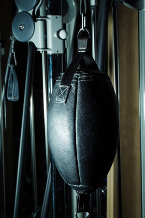 Black leather punching bag, boxing equipment for training, sport, workout hangs in fitness gym on metalized backgroundの写真素材